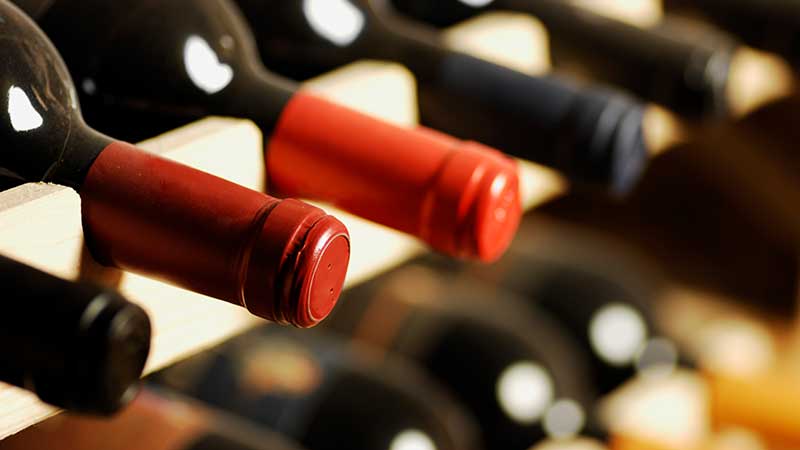 Garrafas de vinho deitadas numa garrafeira de madeira